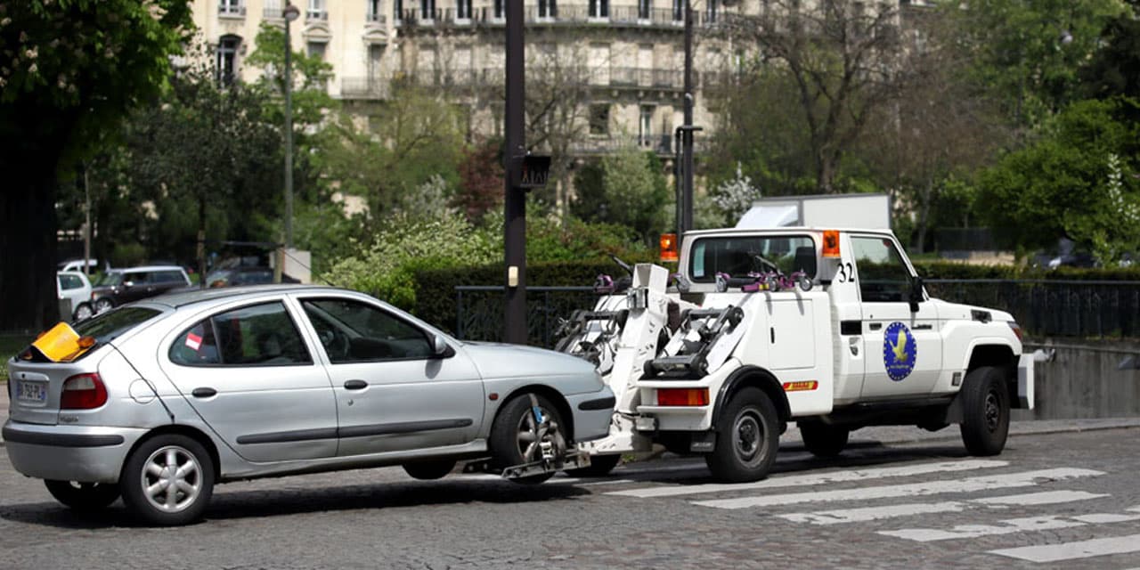 une dépanneuse de fourrière entrain de déplacer un véhicule dans la ville de paris